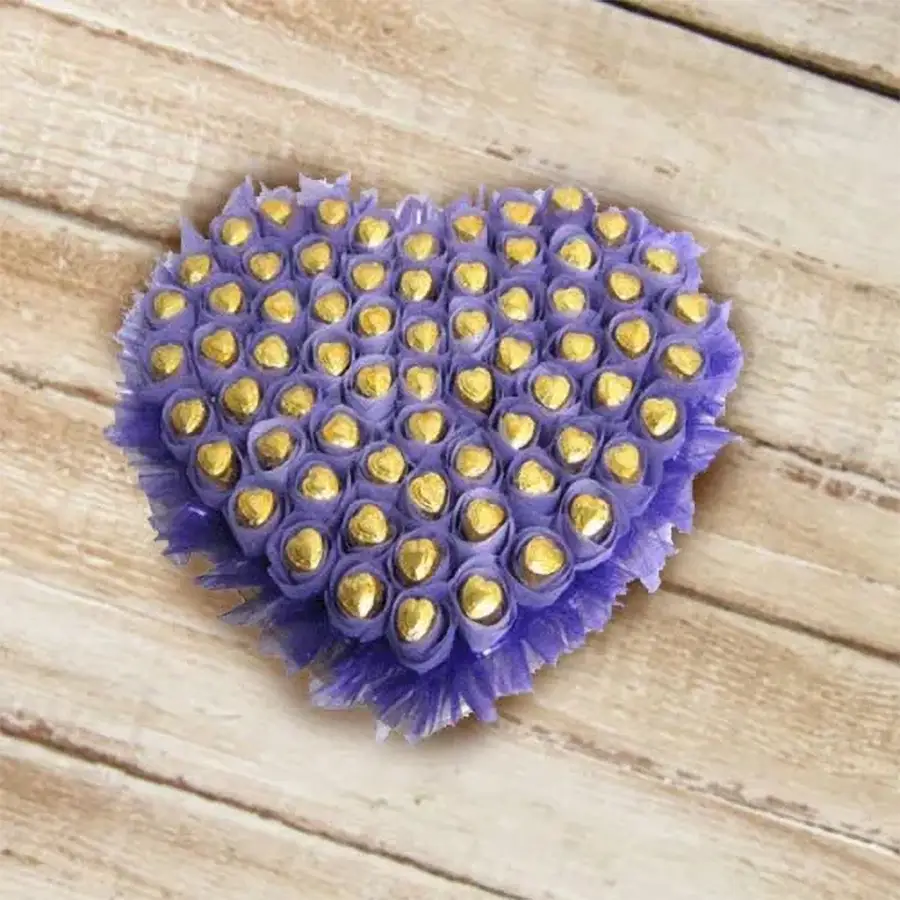 Heart-shaped arrangement of 36 gold-foiled homemade chocolates on purple tissue, elegantly presented for a special occasion.