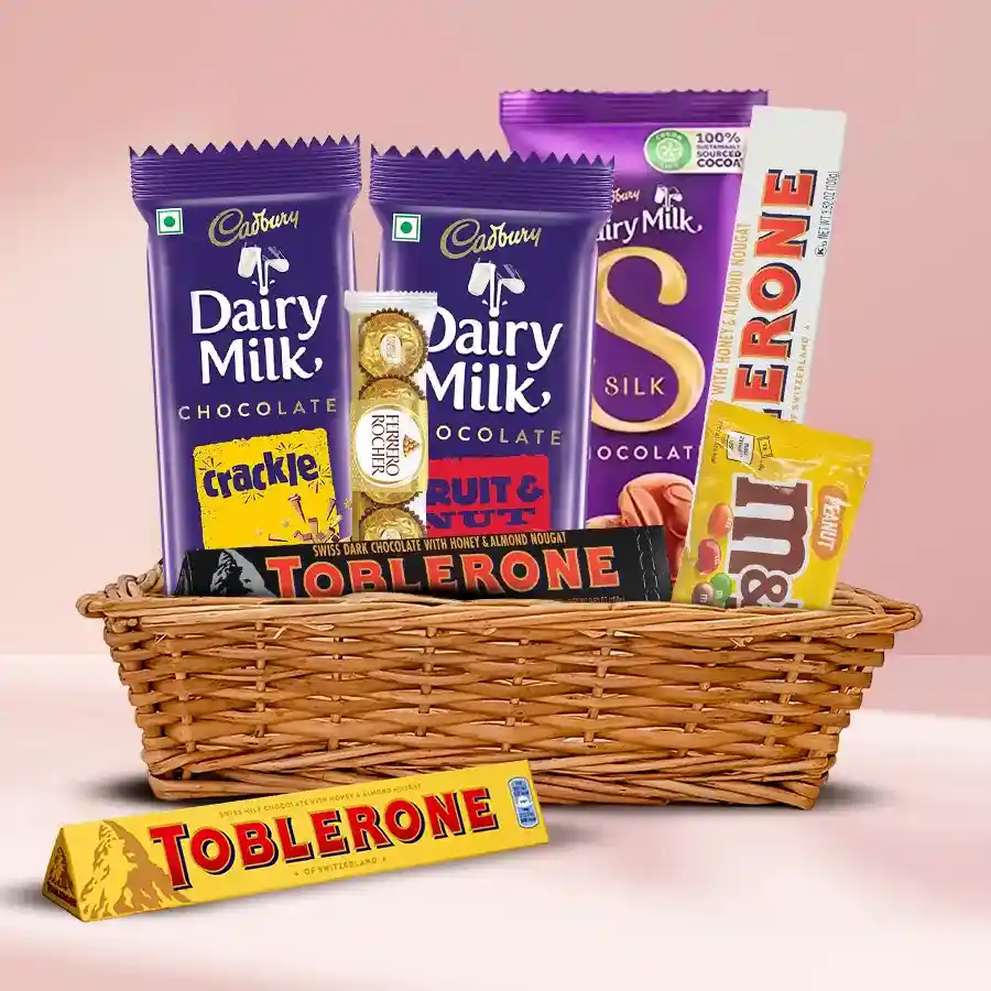 A beautifully arranged chocolate gift basket filled with assorted chocolates including Cadbury Dairy Milk Silk, Toblerone, M&M's with peanuts, and Ferrero Rocher.