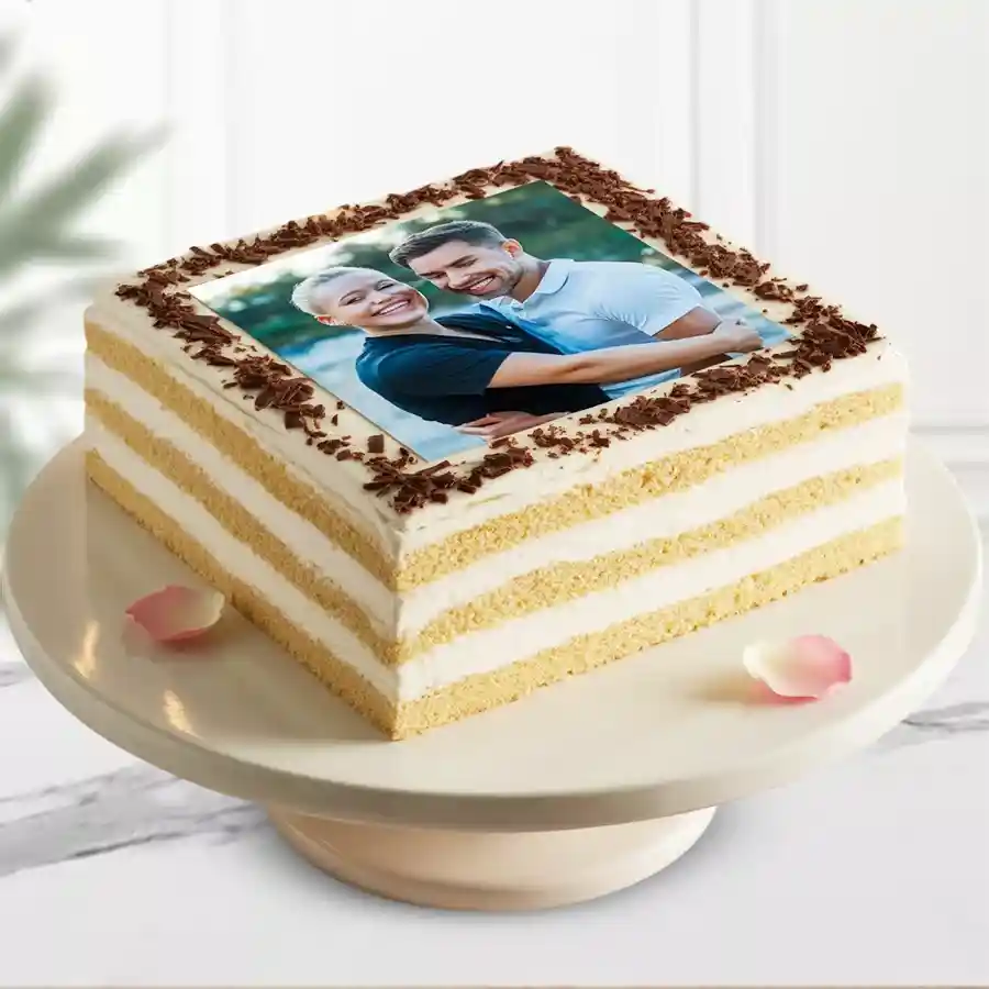 Square vanilla photo cake with cream frosting and chocolate flakes.