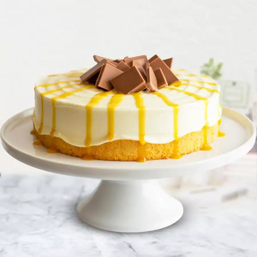 Eggless Mango Cake topped with chocolate thins and mango syrup, beautifully layered on a vanilla sponge base.