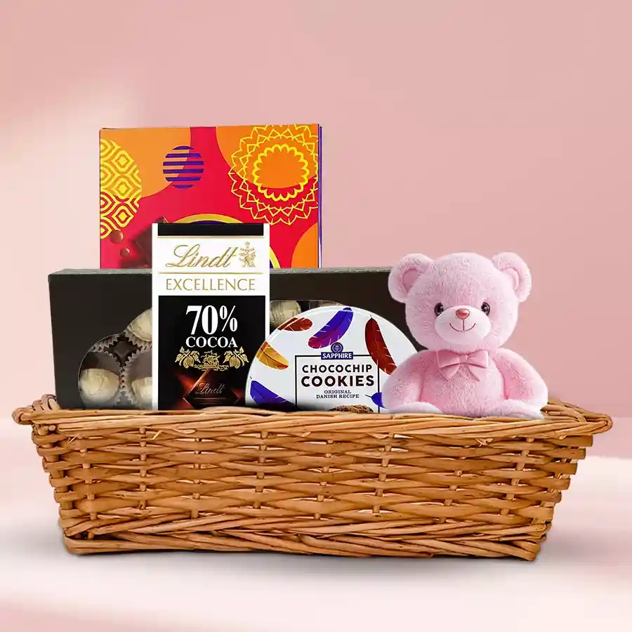 Angelic Chocolate Gift Hamper featuring a 6-inch teddy, Lindt Excellence, Cadbury Celebrations, homemade chocolates, and Sapphire Cookies arranged in a small basket.