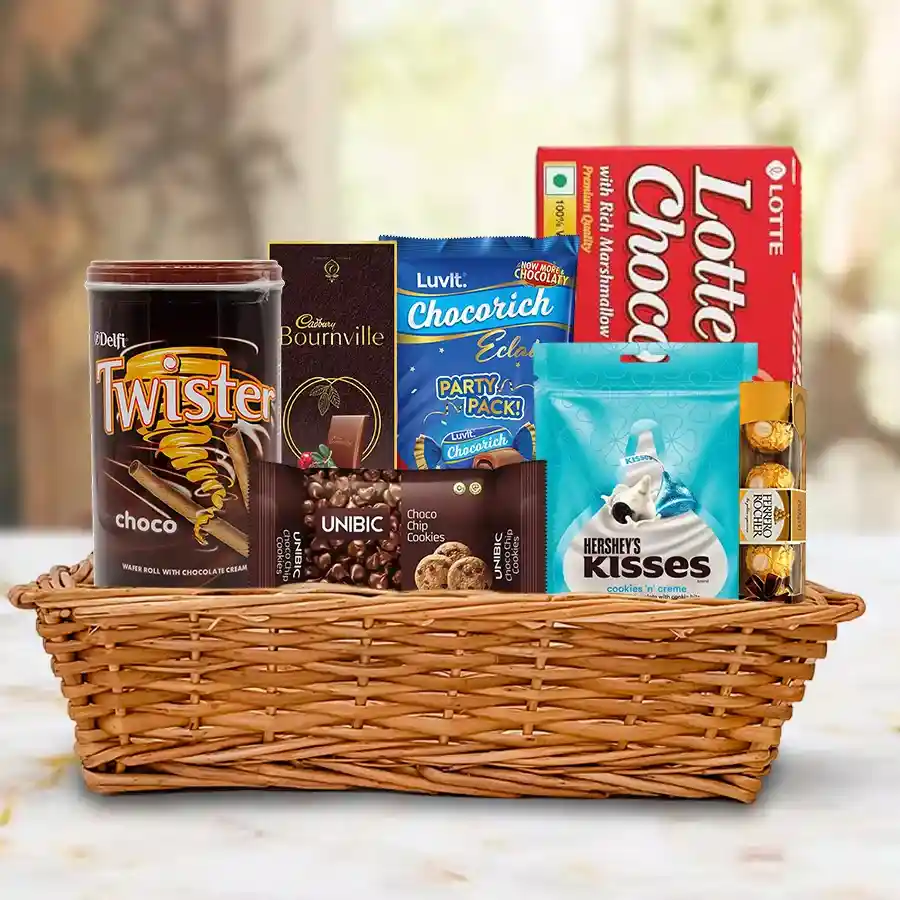 A beautifully arranged basket filled with various chocolates including Chocopie, Cadbury Bournville, Twister Cream Wafers, Luv It Eclairs, Hershey’s Kisses, Unibic Chocolate Cookies, and Ferrero Rocher.