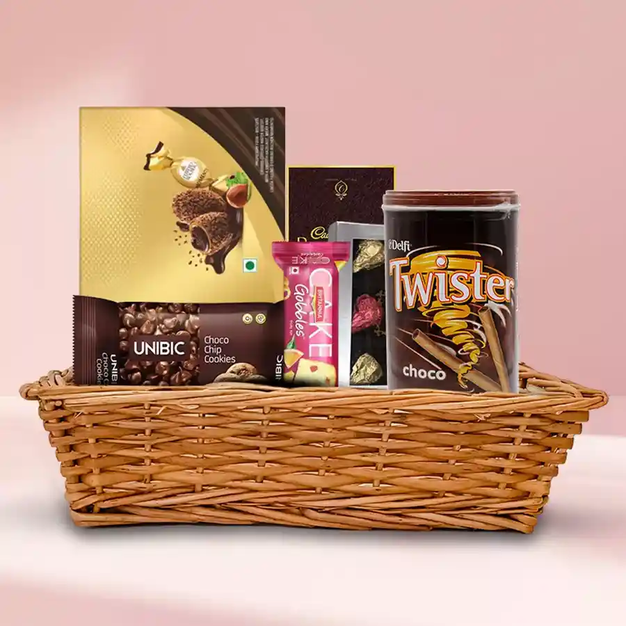 Delectable Chocolate Gift Hamper featuring homemade pineapple-flavored chocolates, Cadbury Bournville, Twister wafers, Unibic cookies, Britannia fruit cake, and Ferrero Moments in a charming basket.