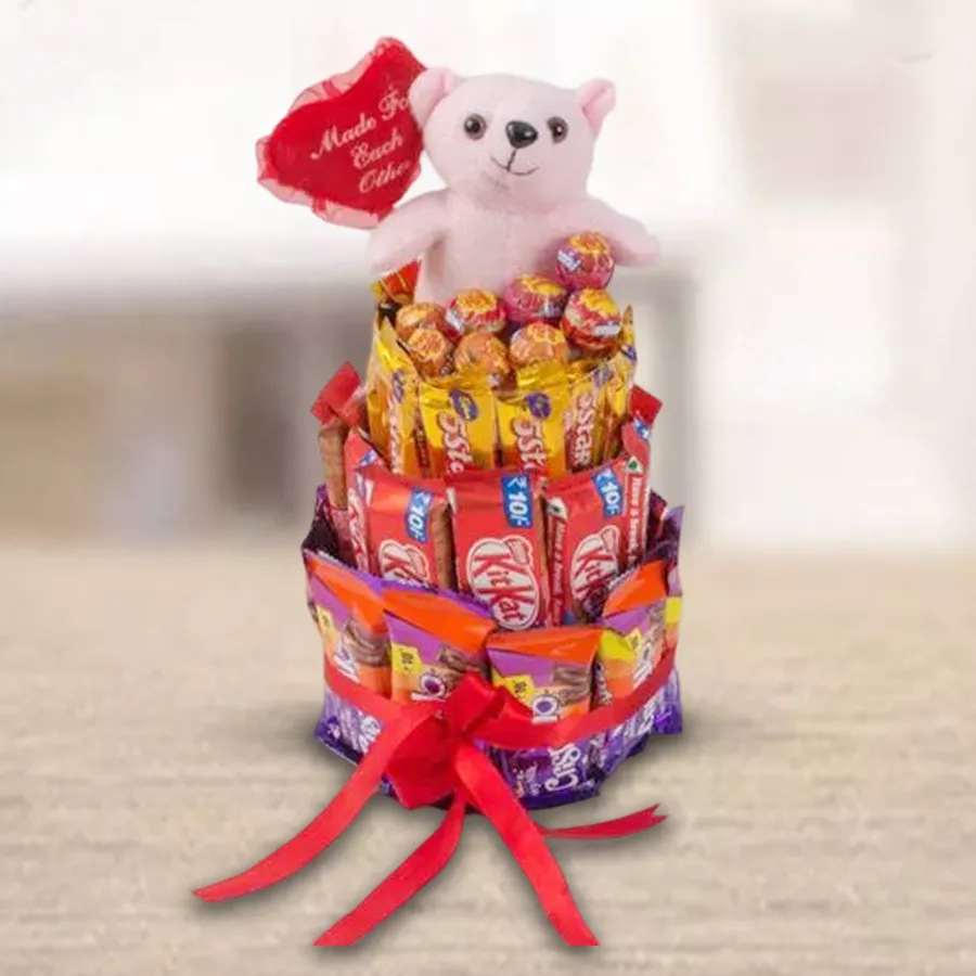 Delightful arrangement of 4 layers of assorted chocolates and a teddy bear, wrapped with a red ribbon
