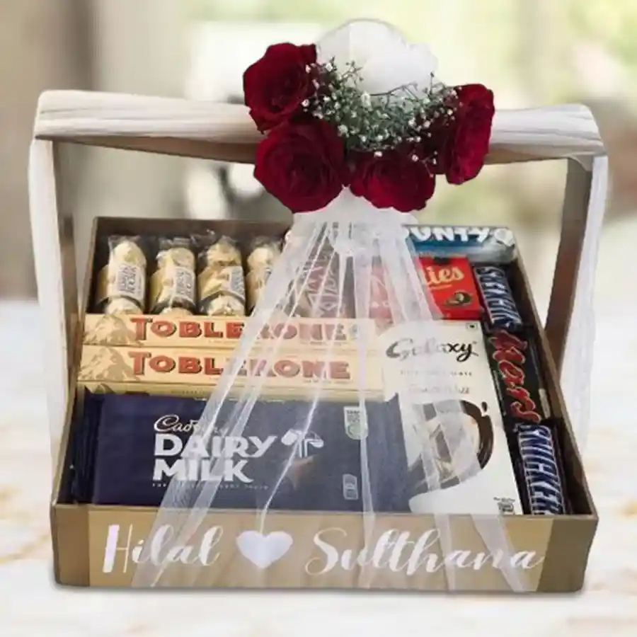 Superb Chocolaty Indulgence Gift Hamper featuring an assortment of Cadbury Dairy Milk, Toblerone, Ferrero Rocher, Twix, Bounty, Snickers, Mars, and Galaxy chocolates in a wooden basket with net tissue and artificial flowers