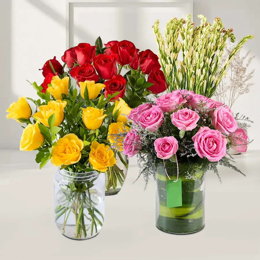 A stunning floral arrangement featuring red, pink, yellow, and tube roses in elegant glass vases, perfect for Valentine's Day.