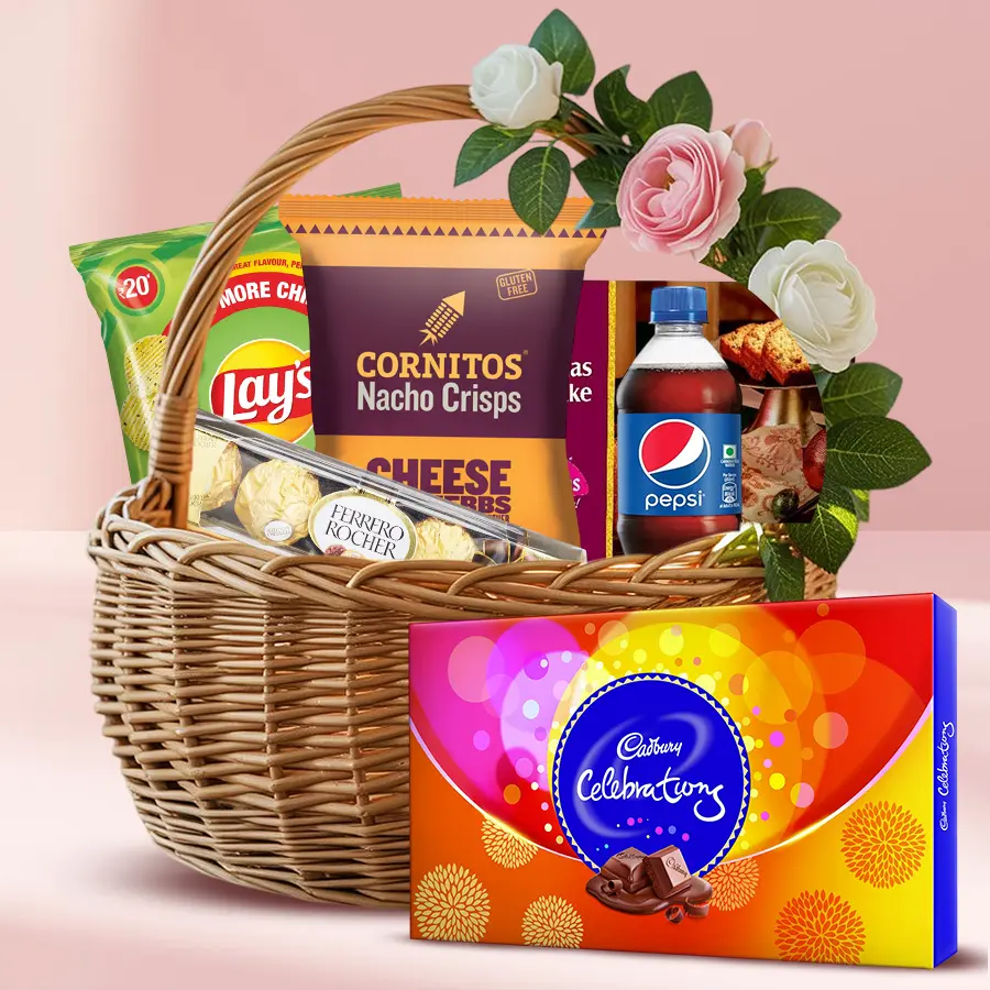 Christmas gift basket filled with festive treats including chocolates, cake, chips, and a refreshing drink, elegantly arranged with flowers.