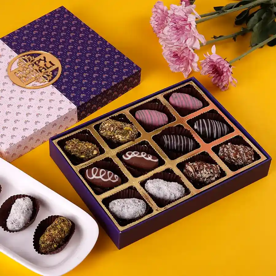A beautifully arranged box of 12 chocolate-covered dates stuffed with almonds, cashews, and pistachios, showcasing rich colors and textures.