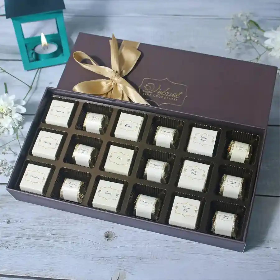 Assorted chocolates in a decorative box, featuring flavors like Oreo, Roasted Almond, Cranberry, Orange Crisp, and Fruit n Nut