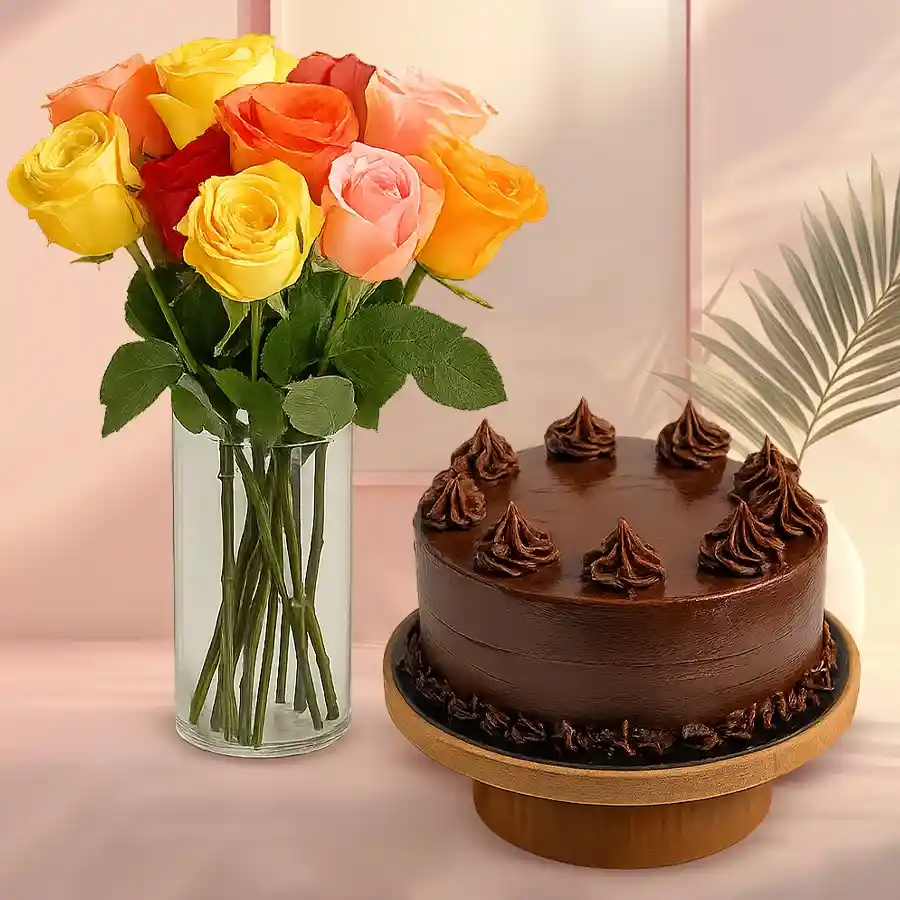 Bouquet of mixed roses in a glass vase with a chocolate cake.