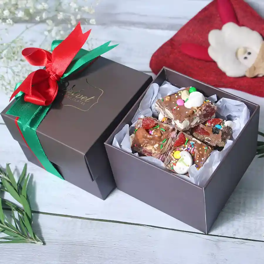 Assorted Christmas chocolates with marshmallows, dried strawberries, cranberries, cashews, almonds, and black raisins in a festive box