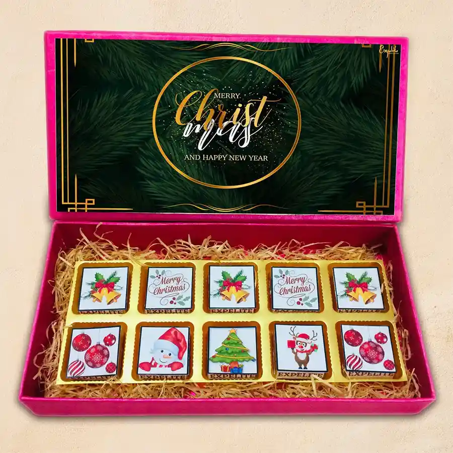 Assorted Christmas-themed chocolates in a beautifully decorated gift box with festive designs and grass accents.
