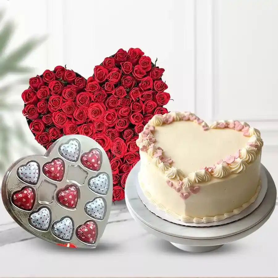 Heart-shaped gift combo featuring 24 red roses, chocolates, and a cake.
