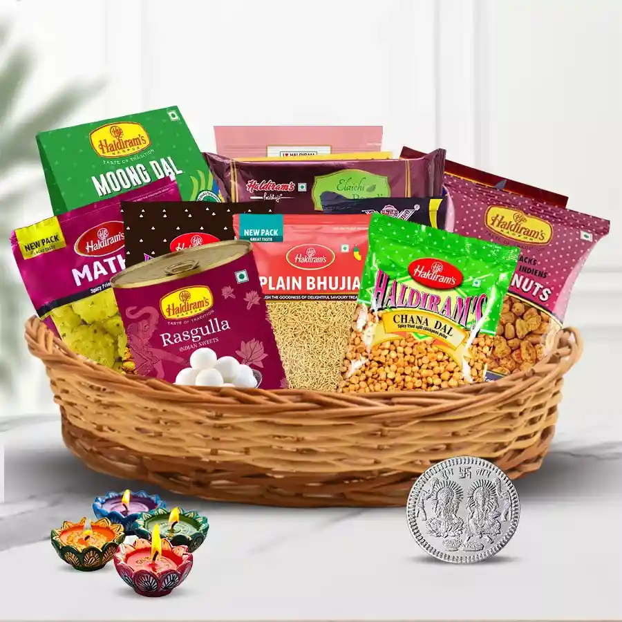 Assorted Snacks Hamper featuring Badam Pakori, Methi Mathari, Khasta Mixture, Kabli Chana, Haldiram's Soan Papri, Rasgulla, Laxmi Ganesh Silver Coin, and four Diyas, all arranged beautifully for Diwali celebrations.