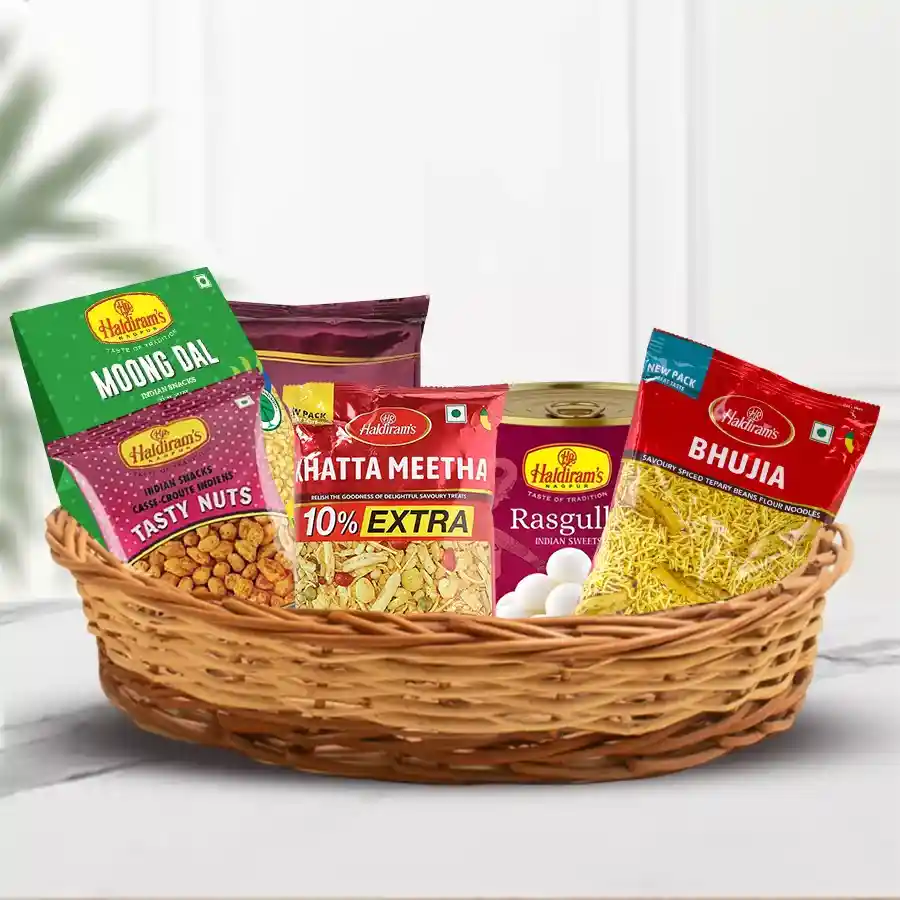 Haldiram Sweet and Snack Basket for Mother's Day featuring Badam Pakodi, Khatta Meetha, Satrang Masala Mixture, Soan Papdi, Rasgulla, Bhujia, and Moong Dal in a cane basket.