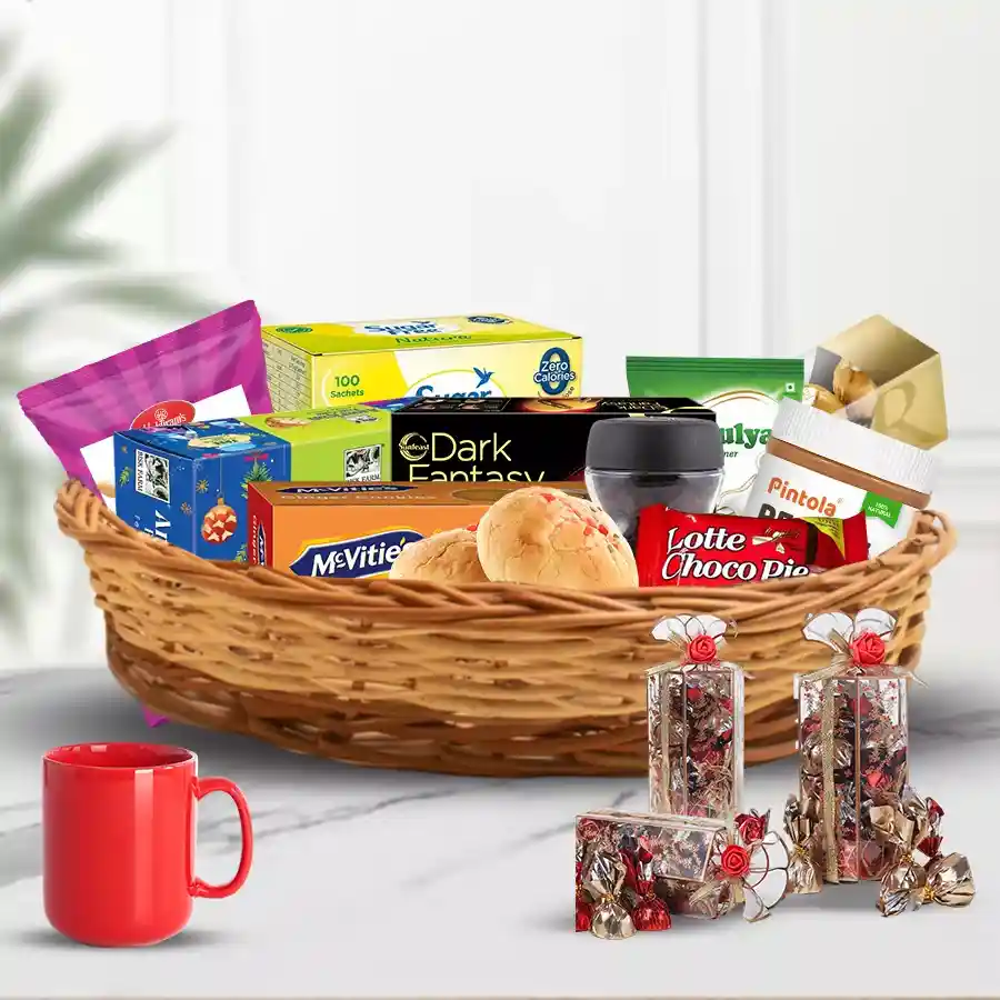 Holiday Charm Christmas Gift Hamper featuring festive treats, including fruit cake, ginger biscuits, peanut butter, coffee, chocolate, handmade sweets, savory snacks, and a coffee mug in a cane basket.