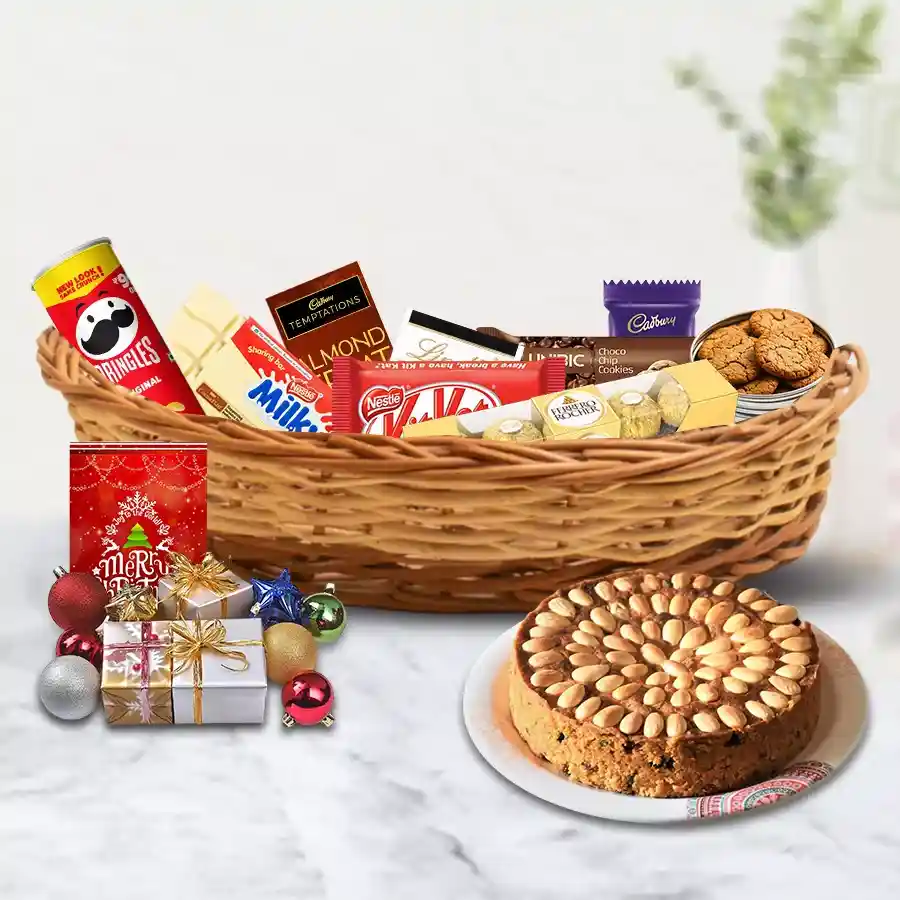 A beautifully arranged Christmas hamper filled with treats like Dundee Fruit Cake, Ferrero Rocher, Lindt, Dairy Milk chocolates, Pringles, Unibic cookies, and decorated with Christmas ornaments and a heartfelt card.