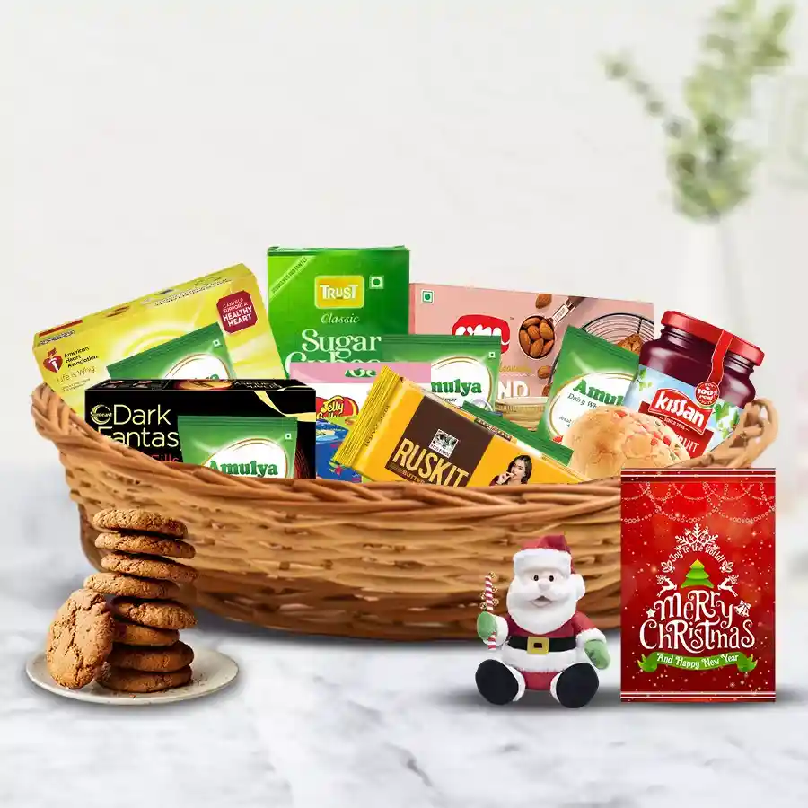 Christmas gift hamper filled with festive treats including fruit cake, biscuits, honey, jam, candies, tea, a Santa soft toy, and more, arranged in a cane basket.