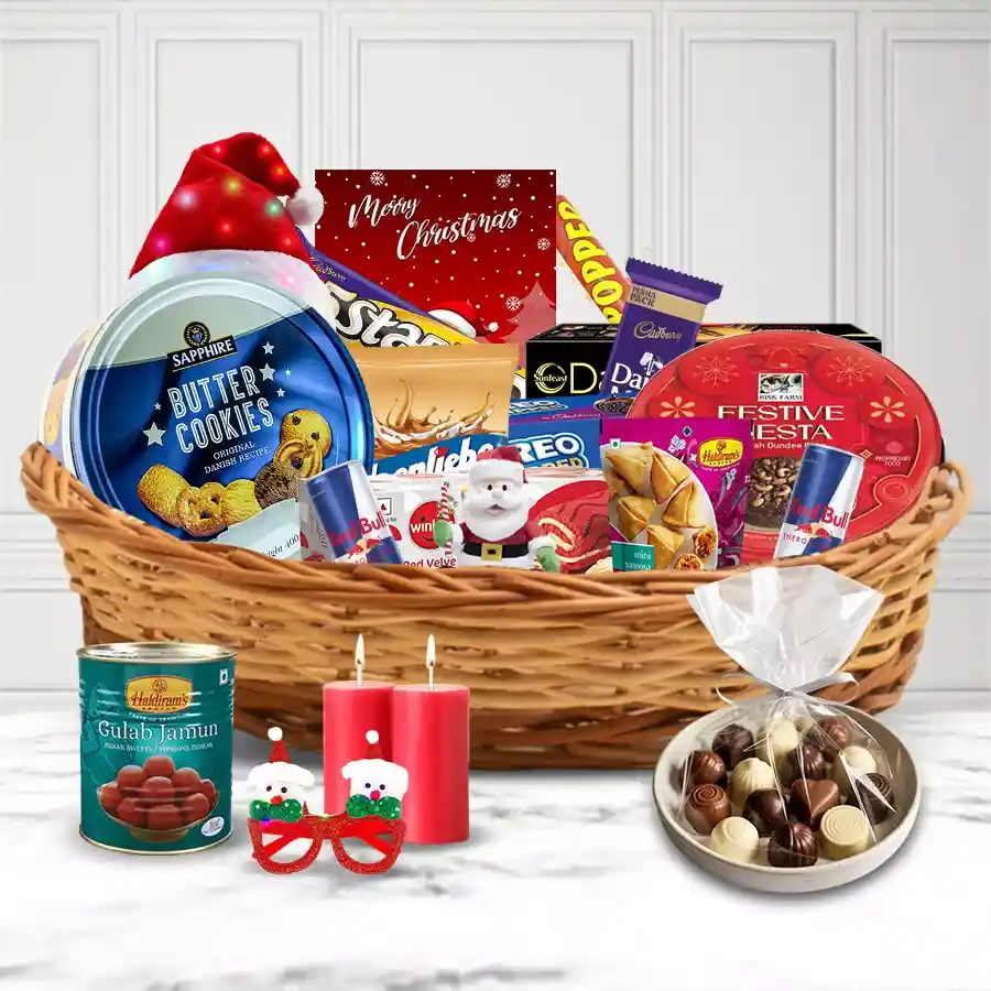 Christmas gift hamper filled with festive treats, including cake, chocolates, snacks, and decorations, arranged in a cane basket.