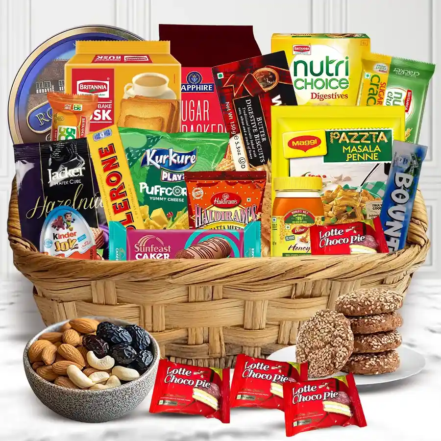 A vibrant gift hamper filled with Britannia Cakes, Nutri Choice grains, Haldirams snacks, assorted biscuits, chocolates including Toblerone and Kinder Joy, crunchy nuts, rich honey, and luscious dates, presented with a cheerful arrangement.