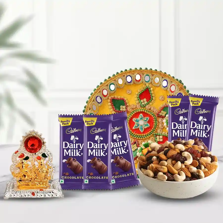 Assorted dry fruits, Cadbury chocolates, pooja thali, and Ganesh Laxmi idol arranged together as a thoughtful gift package.