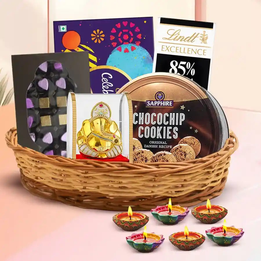 Amusing Diwali Hamper featuring chocolates, cookies, a Ganesh idol, diyas, and a greeting card arranged in a cane basket