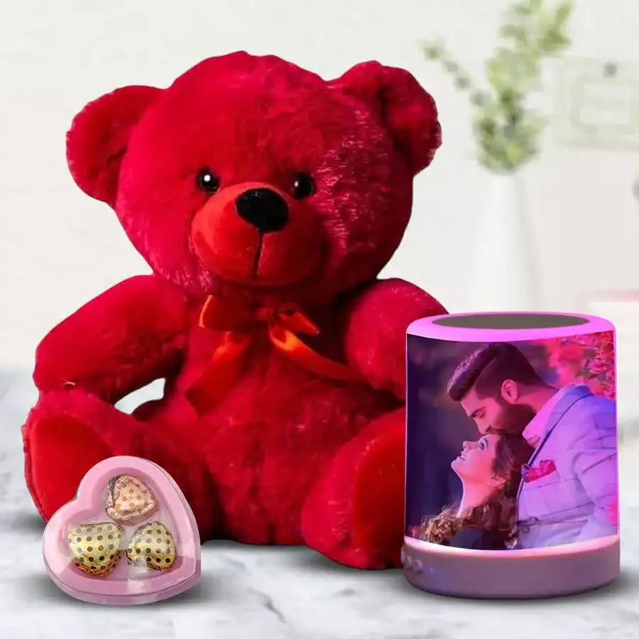 Personalized Bluetooth speaker featuring a favorite photo, accompanied by a red teddy bear and heart-shaped chocolates.