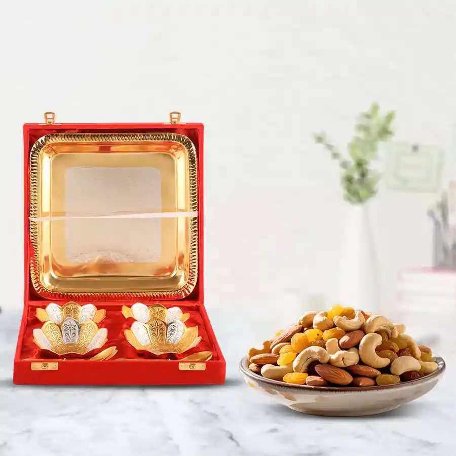 Decorative silver bowl gift set with crunchy dry fruits in a vibrant red bowl placed on a textured surface.