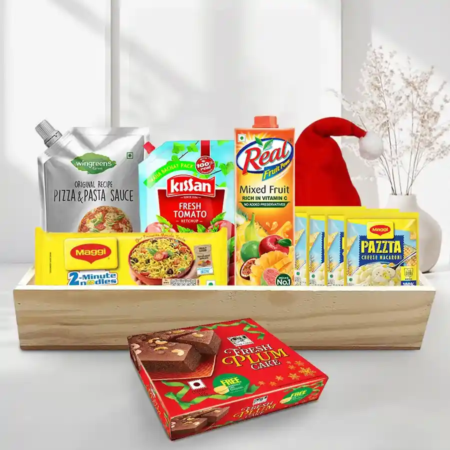 Sensational Breakfast Hamper filled with festive treats including noodles, ketchup, macaroni, sauce, juice, plum cake, a Merry Christmas cap, and a wooden tray.