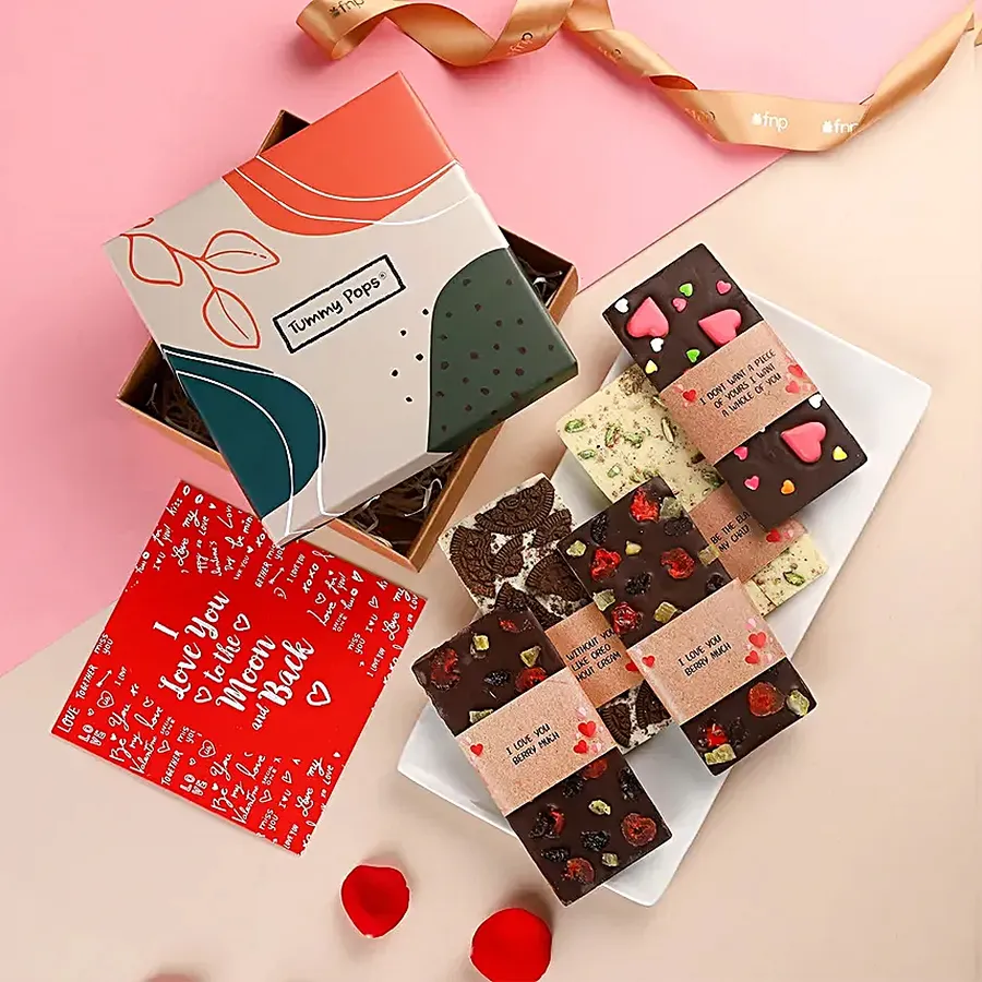 Delectable Chocolate Day Gift Hamper featuring four handmade chocolate bars in Oreo, Berry, Elaichi flavors, a heart-shaped treat, and a greetings card in a decorative gift box.