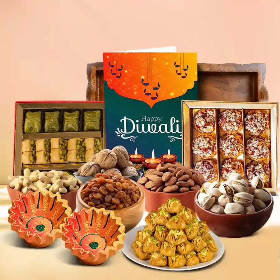 Sensational Diwali Treats N Nuts Hamper featuring cashew, almond, and pistachio baklawa, premium nuts, designer clay diyas, and a Happy Diwali card arranged on a fancy tray