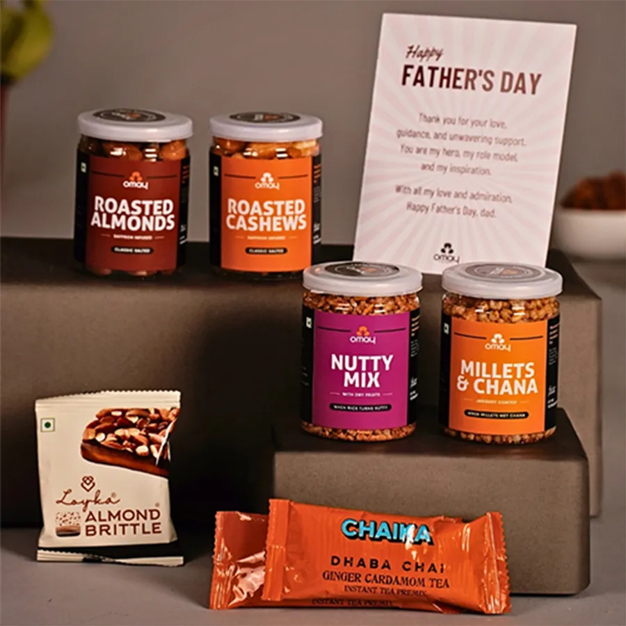 Luxurious snacks and treats hamper for Father's Day including roasted almonds, cashews, nut mix, Millets N Chana, Chaika Instant Tea, Loykas Chocolate Almond Brittle, and a Happy Father's Day card.