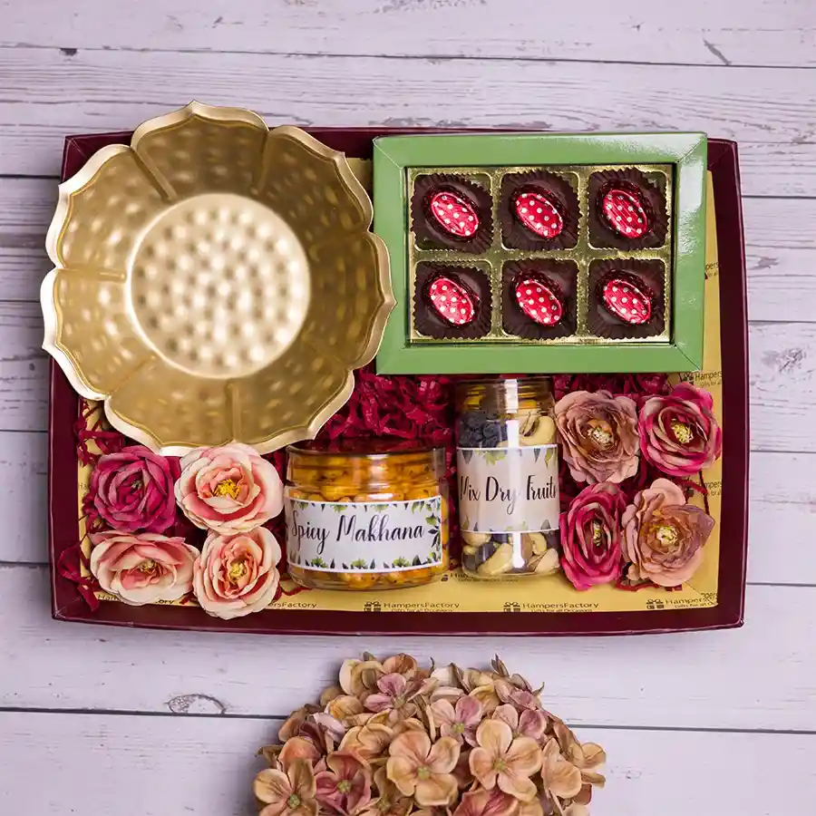 Elegant gift pack featuring a decorative Urli bowl, spicy makhana, a mix of dry fruits, and homemade chocolates in a stylish reusable tray.